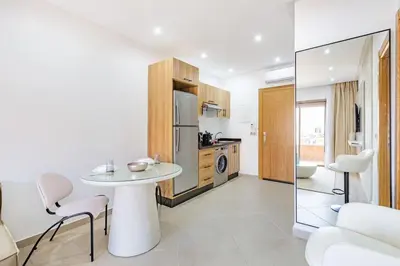a white kitchen with a table and a refrigerator at Appartement chic près de la gare in Marrakech