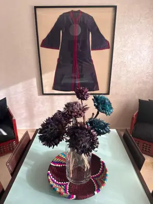 a vase with flowers on a table with a dress at TERRASSE, 2 CHAMBRES SPACIEUSES, 6 COUCHAGES, 2 PiSCINES, PARKING, IDÈAL FAMILLE in Marrakech