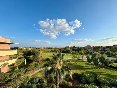 a view of a park with palm trees and buildings at RESIDENCE PRESTIGIA, Piscine, calme et verdure in Marrakech