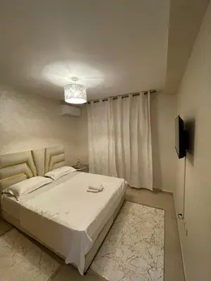 a bedroom with a white bed and a television at Vivez le rêve dans un appartement F4 moderne in Marrakech