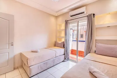 two beds in a room with a window at 2 chambres dans la ville rouge in Douar Bellouk