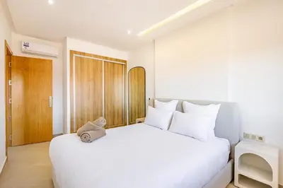 a white bedroom with a large white bed with white pillows at Escapade intime en ville rouge in Marrakech