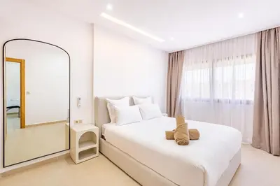 a white bedroom with a large mirror and a bed at Escapade intime en ville rouge in Marrakech