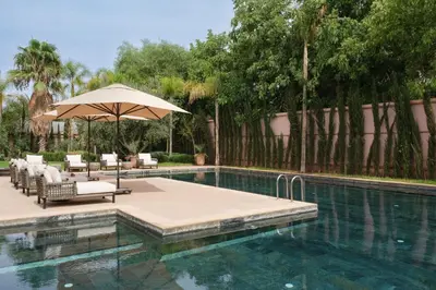 a swimming pool with chairs and an umbrella next to a swimming pool at Villa Yali in Marrakech