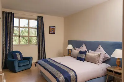 a bedroom with a bed and a blue chair and a window at Villa Monica in Marrakech