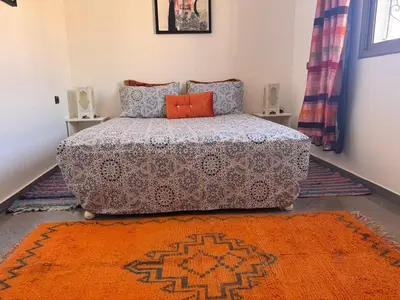a bedroom with a bed and an orange rug at appartement lumineux familial, vue sur l'océan avec wifi rapide in Marrakech