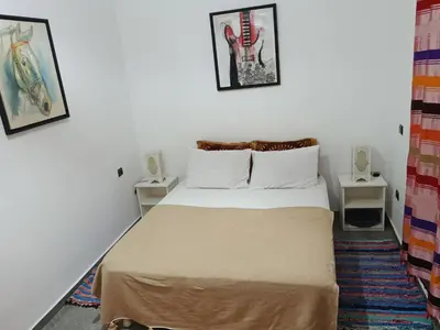 a small bedroom with a bed and two tables at appartement lumineux familial, vue sur l'océan avec wifi rapide in Marrakech