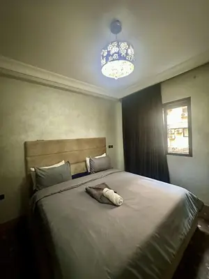 a bedroom with a large white bed with a chandelier at studio équipé et centrale -Guéliz in Marrakech