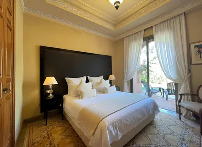 a bedroom with a large white bed with a large window at La perle de la palmeraie in Marrakech