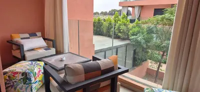 a balcony with a chair and a table and a window at Domaine de noria in Marrakech