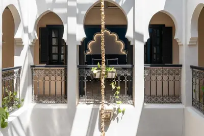 a white building with a balcony with a plant at Riad azzouina in Marrakech