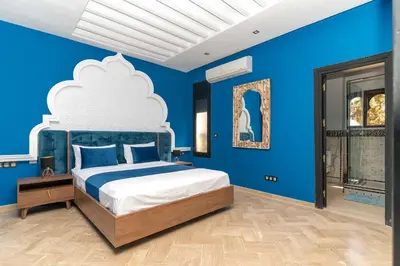 a blue bedroom with a large bed with a white headboard at Riad azzouina in Marrakech