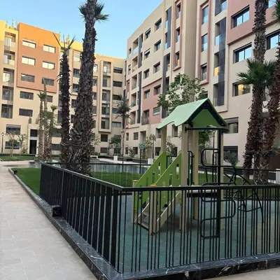 a playground in a park with palm trees and buildings at Residence hôte standing Marrakech Gueliz in Marrakech