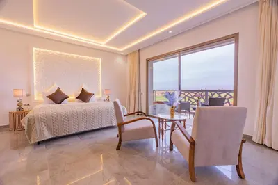 a bedroom with a bed and a table and a large window at Golfside Villas in Marrakech