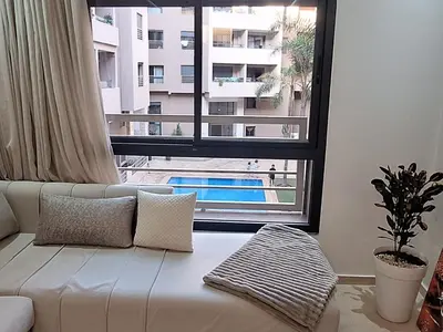 a white couch in a living room with a large window at Appartement Moderne Centre Gueliz Sunny Pool PS4 & Wi-Fi in Marrakech