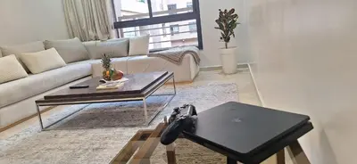 a living room with a couch and a table with a laptop at Appartement Moderne Centre Gueliz Sunny Pool PS4 & Wi-Fi in Marrakech