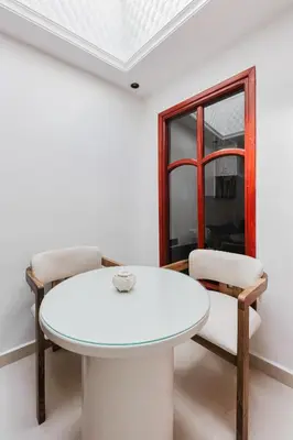 a white dining room with a white table and two chairs at Maison Joudia in Marrakech