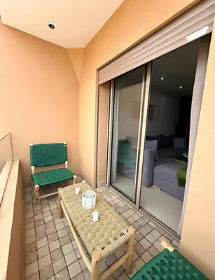 a room with a balcony with a table and a couch at Central Gueliz Apartment Walk to Train Station in Marrakech