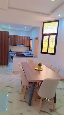 a kitchen and dining room with a wooden table and chairs at Appartement Aéroport Suite Marrakech-M9 in Marrakech