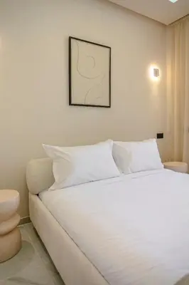 a bedroom with a white bed with a picture on the wall at The Crown Edition - Hivernage Marrakech in Marrakech