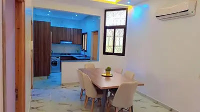 a kitchen and dining room with a wooden table and chairs at Appartement Aéroport Palm Marrakech-M9 in Marrakech