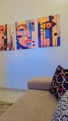two paintings hanging on a wall above a bed at Appartement Aéroport Sunset Marrakech in Marrakech