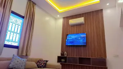 a living room with a couch and a tv on a wall at Appartement Aéroport Center Marrakech in Marrakech