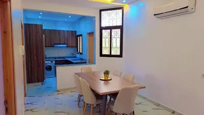 a kitchen and dining room with a wooden table and chairs at Appartement Aéroport Center Marrakech in Marrakech