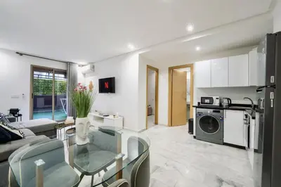 a living room with a glass table and a kitchen at Terrace & Fast Wi-Fi - Stylish city center flat - Gueliz in Marrakech