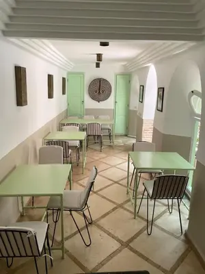 a dining room with green tables and chairs at Riad Birdy, Charmant et privatif, Piscine, Rooftop, 6 suites, 2 salons, Wifi in Marrakech