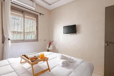 a white room with a white couch and a tv at Moroccan Comfort & Charm - 10 min from Guéliz in Marrakech