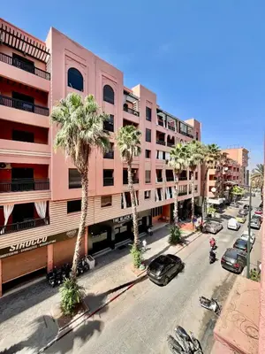 a street with palm trees in front of a pink building at Perfect stay in Guéliz Book now! in Marrakech