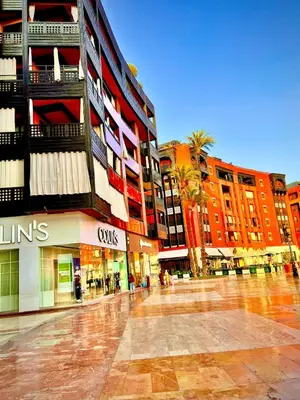 a city street with tall buildings and palm trees at Appartement Plaza Centre in Marrakech