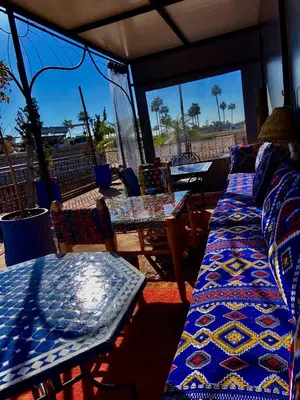 a room with two beds and a table and windows at Dar Koutobia Stars in Marrakech