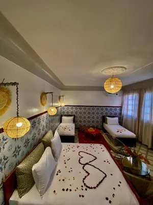 a bedroom with two beds and a couch and chandeliers at Dar Koutobia Stars in Marrakech