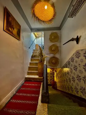 a hallway with a red carpet and stairs with a chandelier at Dar Koutobia Stars in Marrakech