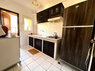 a kitchen with black cabinets and a white tile floor at Charming apartment with a traditional style in Marrakech