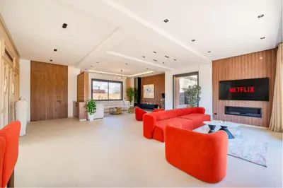 a living room with orange furniture and a tv at Luxury 5-Suite Villa with private pool in GOLF Amlkis ,free Airport transport service in Marrakech