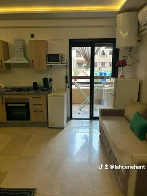 a living room with a couch and a kitchen with a refrigerator at Studio confort à Hivernage Piscine, parking & toutes commodités in Marrakech