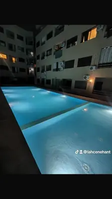 a large blue swimming pool in front of a building at Studio confort à Hivernage Piscine, parking & toutes commodités in Marrakech