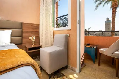a bedroom with a bed and a chair and a window at Résidence Qodwa in Marrakech
