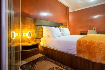 a bedroom with a bed and a glass shower at Résidence Qodwa in Marrakech