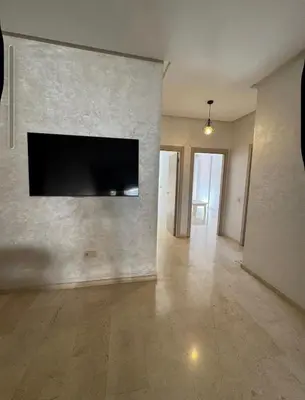 an empty living room with a flat screen tv on a wall at Marrakech résidence Nour 6 in Marrakech