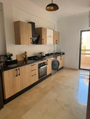 a large kitchen with wooden cabinets and a dishwasher at Marrakech résidence Nour 6 in Marrakech