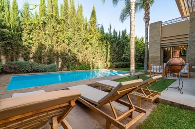a backyard with a swimming pool and two lounge chairs at Zen Villa Private Parking in El Rhechat