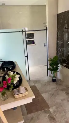 a bathroom with a shower and a sink with flowers at Villa LAM atlas view in Tameslouht