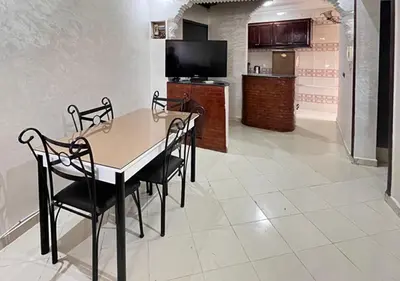 a dining room with a table and chairs and a kitchen at Séjour confortables et proche de tous in Marrakech