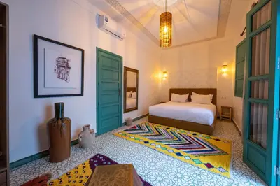 a bedroom with a bed with green doors and a rug at Riad Nejma Benyoussef in Marrakech