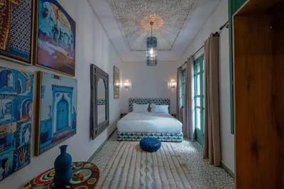 a bedroom with a bed and paintings on the walls at Riad Nejma Benyoussef in Marrakech