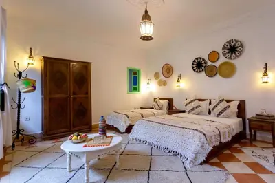 a bedroom with two beds and a table at Riad Rose Meryam in Marrakech